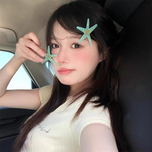 Détail d'une barrette étoile de mer vert menthe avec étoile dorée sur les cheveux d'une femme