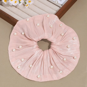 Détail du chouchou en satin rose avec perles blanches et texture satinée brillante