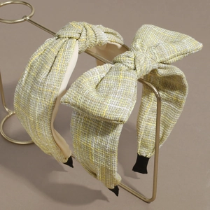 Elegant yellow and white tweed headband set with bow and knot detail on gold stand