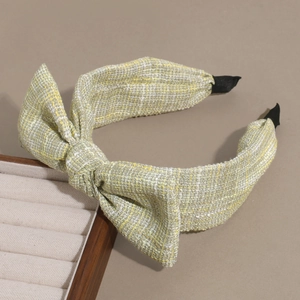 Detail of tweed bow headband in yellow and white plaid with protective fabric end tips
