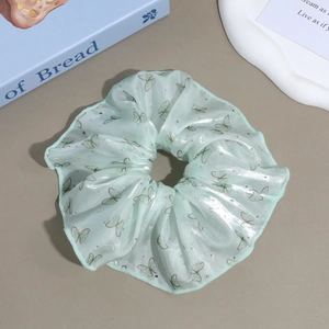Detail of light green floral scrunchie with butterfly print and rhinestone accents