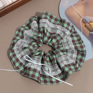 Detail of green plaid scrunchie with white heart lace trim and small satin bow detail