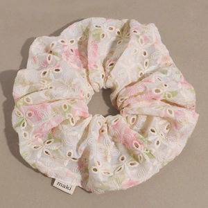 Detail eines bestickten floralen Haargummis mit Maki-Etikett und feiner Stickerei