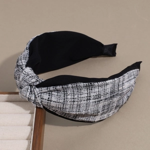 Detailed close-up of a wide black and white tweed headband with an elegant top knot