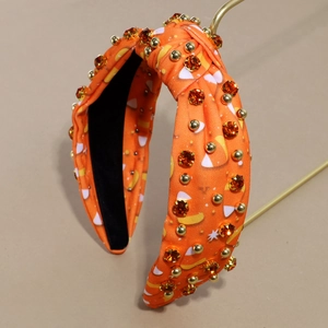 Dettaglio del cerchietto arancione a nodo con strass sfaccettati e borchie d'oro