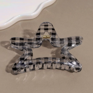 Detailed close-up of a star-shaped hair claw clip with black and grey plaid patterns