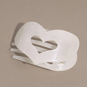 Dettaglio della molletta per capelli a cuore bianco perlato con finitura glitter