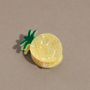 Détail de la pince à cheveux ananas jaune avec finition perlée et motif de feuille verte