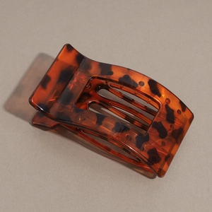 Detail view of the tortoiseshell flat hair claw clip with amber resin texture and rounded teeth