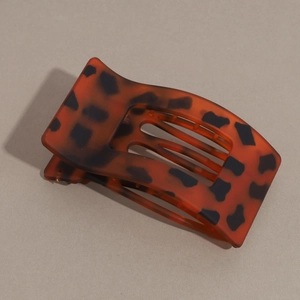 Detail view of tortoiseshell claw clip with matte texture and curved hollow design