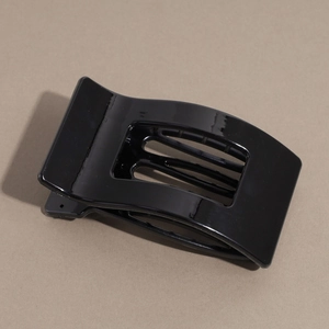 Detail of a sleek black arched hair claw clip with a glossy finish and metal spring mechanism