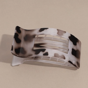 Detailed view of the black and white spotted cow print hair claw clip on a neutral background