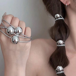 Minimalist silver spherical elastic hair tie and metallic ring accessory on hair and wrist