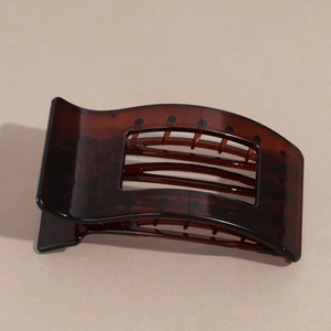 Macro shot of large amber resin hair claw clip with rectangular cutout and glossy finish