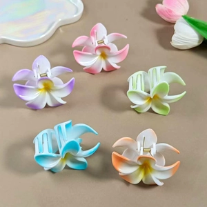 Close-up of five gradient frangipani flower hair claws in multiple colors for hair styling
