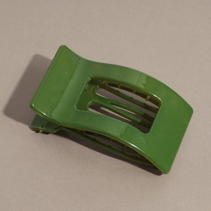 Detailed view of large dark green hair claw clip with glossy resin finish and spring mechanism