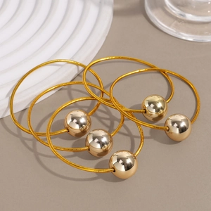Five gold elastic hair ties with glossy mirror metallic ball charms on a white display