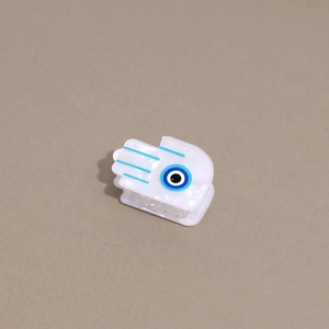 Macro view of Hamsa hand hair claw clip in pearl white with blue evil eye detail