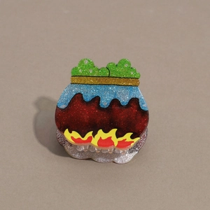 Macro detail of Halloween witch cauldron hair claw with glitter finish and flame design