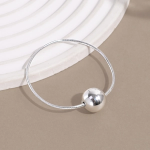 Detailed shot of a silver ball slider on a snake chain hair tie over a clean pedestal