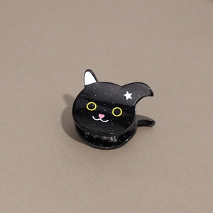 Detail of black cat hair claw clip with star glitter finish and yellow eyes