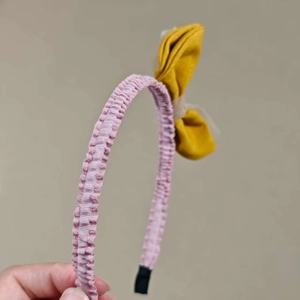 Pink striped headband with a bright yellow fabric bow and comfortable protective ends