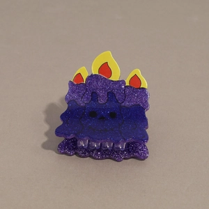 Detail of purple glitter candle hair claw clip with melting wax effect and cartoon face