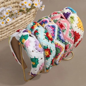 Handmade crochet floral wide headbands in various colors displayed on a gold metal stand