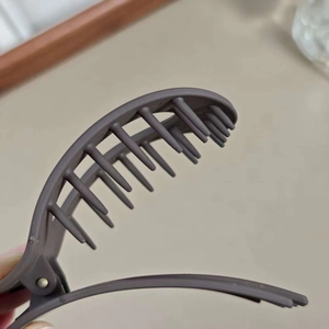 Pince à cheveux ovale marron mat au design plat minimaliste pour un maintien confortable