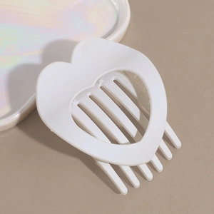Detail view of model KY-137 white heart hair clip with hollow design on beige background
