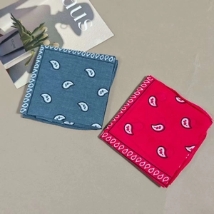 Detailed view of red and grey-blue paisley bandanas folded on a minimalist surface