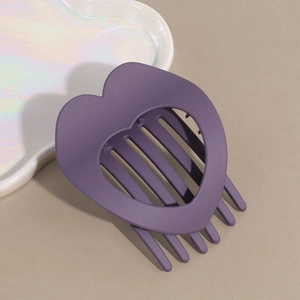 Macro shot of matte purple heart-shaped hollow hair claw clip with rounded teeth texture