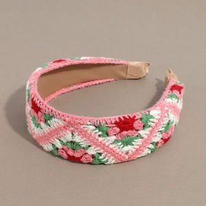 Detailed macro view of handmade pink knit headband with floral crochet patterns