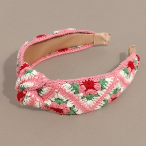 Close-up of pink and white crochet floral patterns and top knot detail on headband