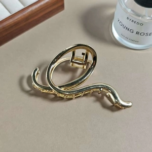 Macro shot of minimalist golden alloy hair claw with sleek wavy curves and glossy finish