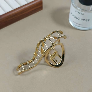 Elegant gold wave-shaped alloy hair claw clip with a polished finish for bun hairstyles