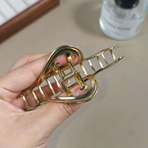 Close-up of golden alloy hollow heart-shaped hair claw clip with metal spring