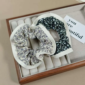 Détail de chouchous à fleurs en beige et noir présentés dans un coffret cadeau en bois