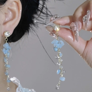 Detail of elegant gold tassel earrings with light blue crushed stone beads and zircon
