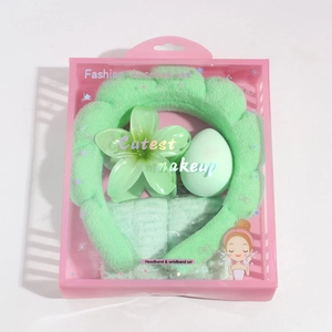 Detail view of light green spa headband and wristband set in a clear gift box packaging
