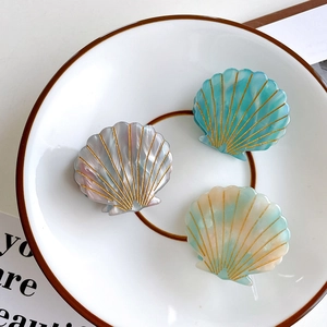 Shell-shaped acetate hair claw set in marbled grey, turquoise, and pastel green tones