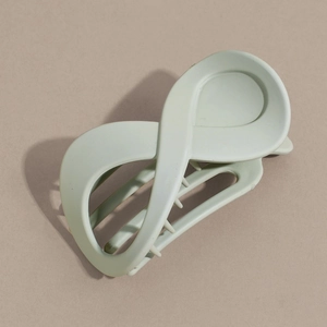Détail d'une pince à cheveux vert sauge mat en forme d'infini avec des dents antidérapantes