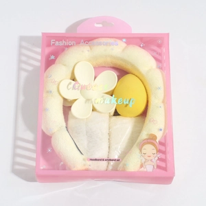 Pink gift box set with yellow sponge headband, white wristbands, floral clip, and makeup egg