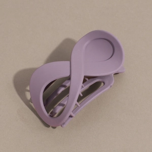 Détail d'une pince à cheveux mate violette en forme d'infini sur fond neutre