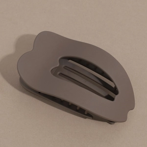 Macro shot of dark brown matte hair claw clip with curved hollow heart-shaped design