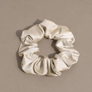 Close-up of champagne silk satin scrunchie showing glossy texture and soft folds