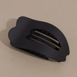 Close-up of a matte black hair claw clip with curved design and hollow slots for women