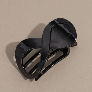 Vue rapprochée d'une pince à cheveux noire brillante en forme d'infini avec dents de maintien