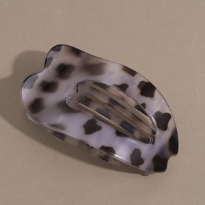 Macro detail of large grey leopard print hair claw clip showing curved flat heart design