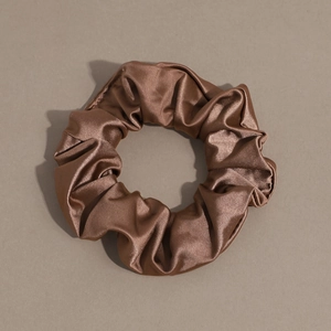 Close-up of brown textured satin scrunchie showing detailed pleated fabric and glossy finish